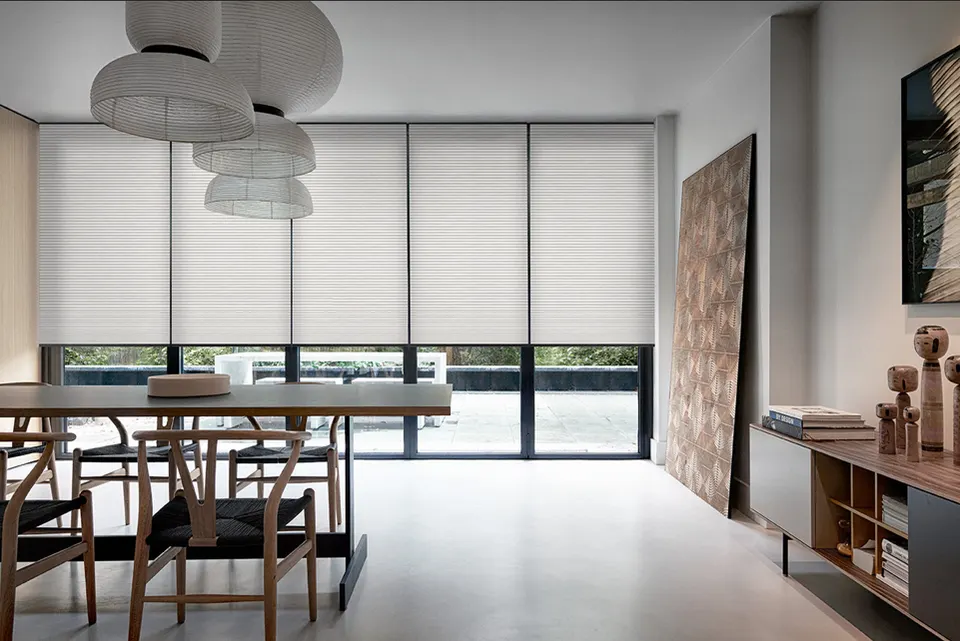 Honeycomb blinds across floor-to-ceiling windows in a dining room