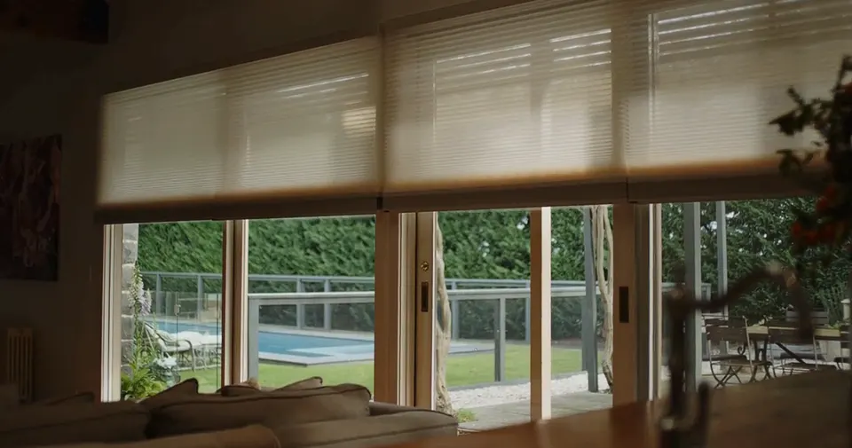 Honeycomb blinds part lowered over a garden view