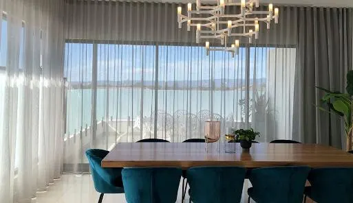Sheer curtains across a dining room with a water view