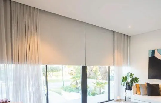 Roller blinds layered with sheer curtains in a living room