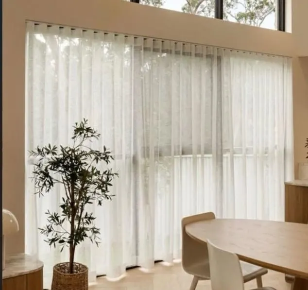 Full-height sheer curtains in a double-height dining room