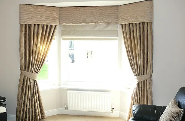 Upholstered pelmet across a bay window with tied-back curtains