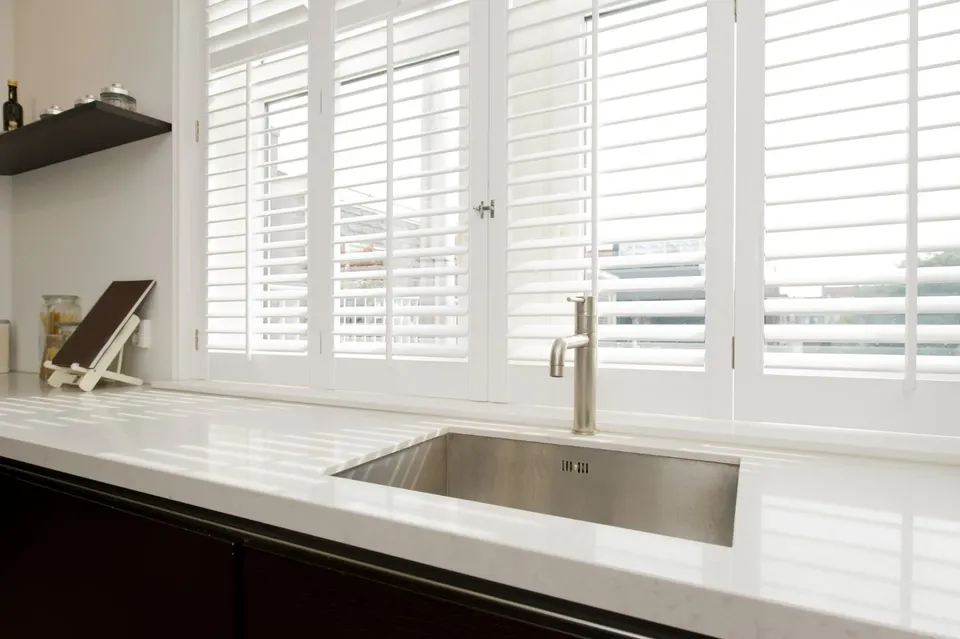 White plantation shutters above a kitchen sink